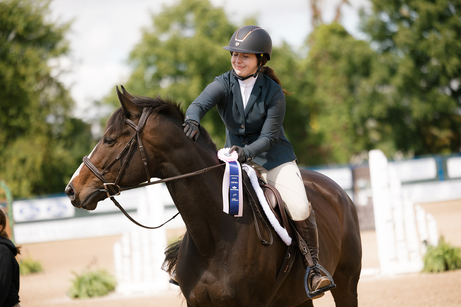 Rider patting horse with sixth place ribbon on necj